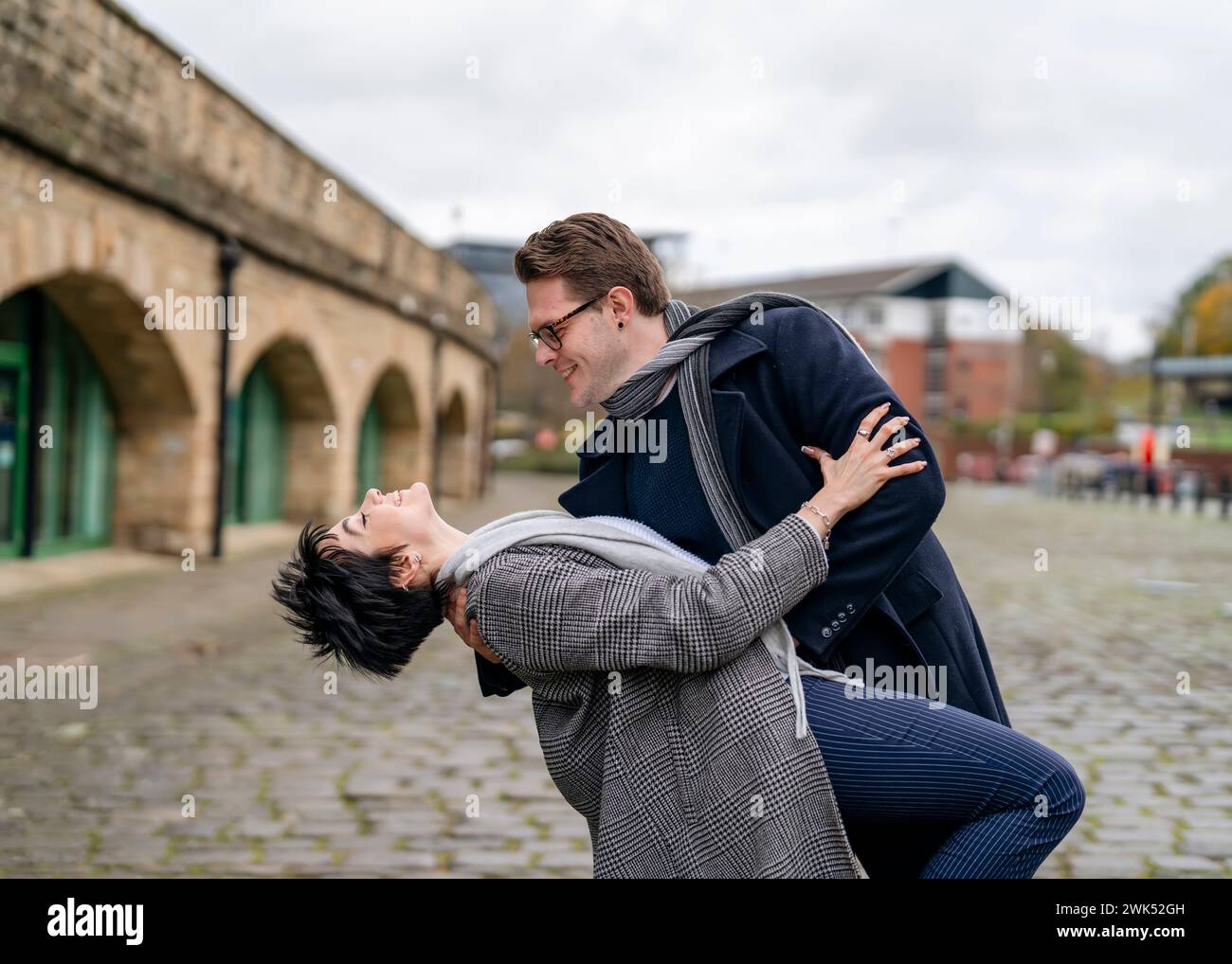 Ein gutaussehender Mann und eine schöne Frau umarmen sich, während sie durch die Stadt laufen, auf der Straße tanzen und am Herbsttag eine lustige Zeit verbringen. Lifestyle ph Stockfoto