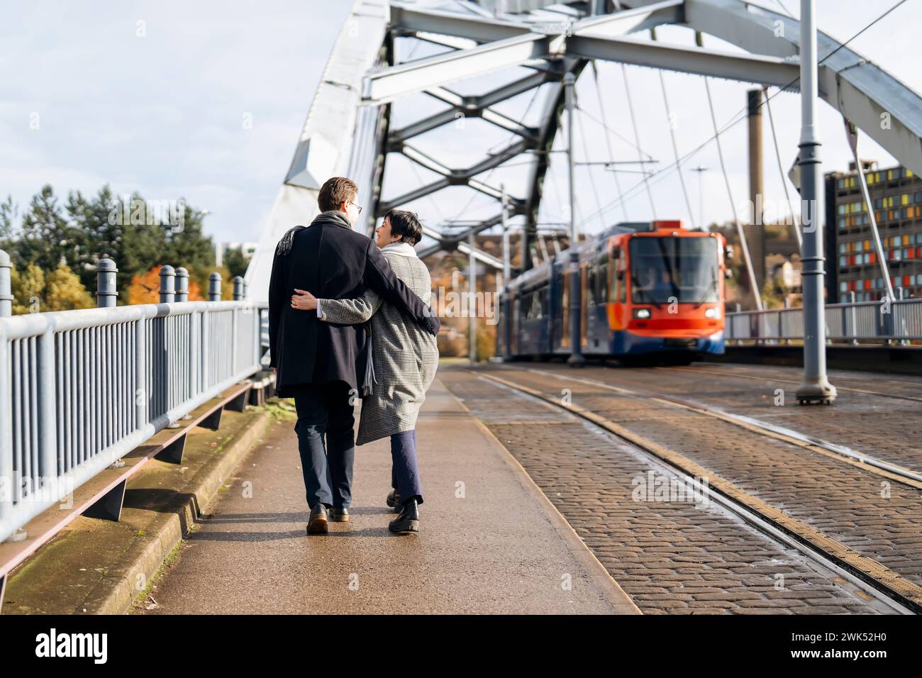 Gutaussehender Mann und schöne Frau umarmen sich gegenseitig, während sie durch die Stadt laufen, eine Brücke überqueren, Spaß haben, Lifestyle-Foto Stockfoto