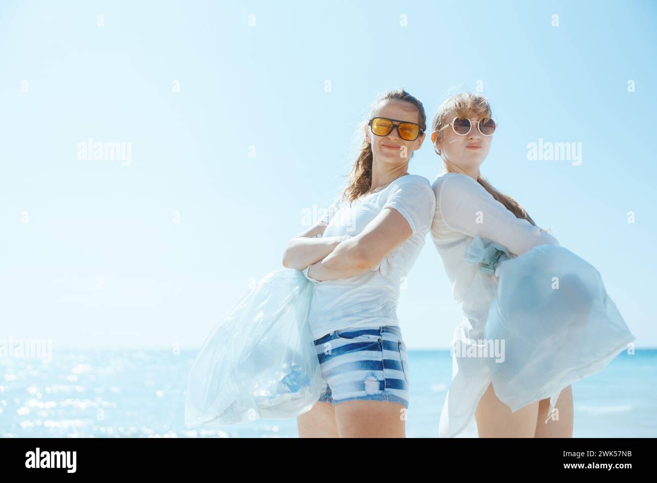 Glückliche Frauen arbeiten an der Küste mit Müllsäcken und sammeln Müll. Stockfoto