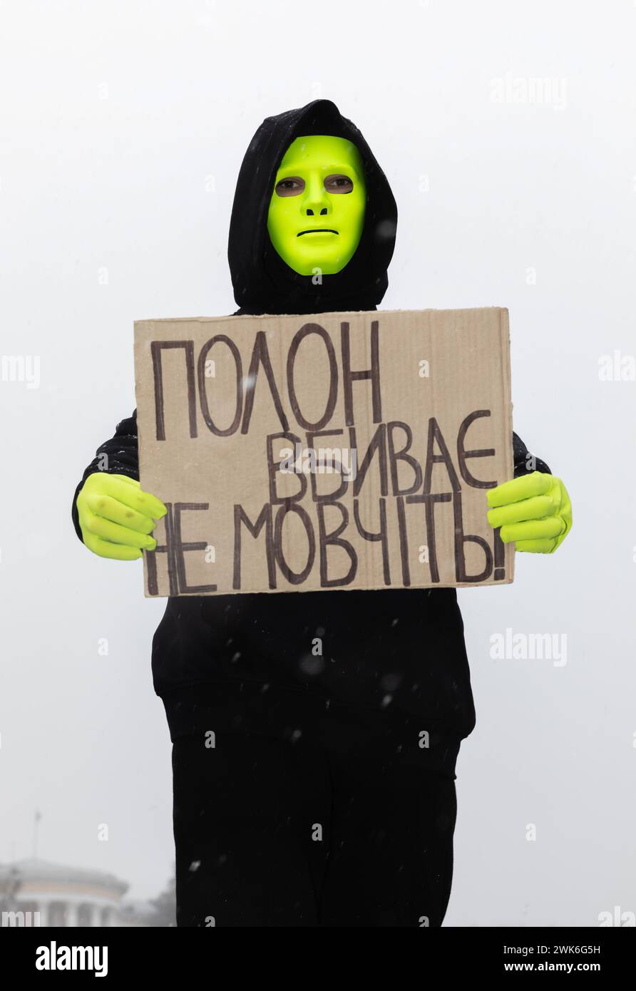 Ein Mann in einer Maske hält ein Plakat mit der Aufschrift "nicht schweigen - Gefangenschaft tötet" während einer Kundgebung auf Maidan Nezalezhnosti. Am Sonntag fand auf dem Maidan Nezalezhnosti in Kiew die traditionelle Freie Asow-Kundgebung von Verwandten und Freunden gefangener Soldaten statt. Verwandte und Freunde von gefangenen ukrainischen Soldaten kamen zu der Kundgebung, um uns daran zu erinnern, dass das ukrainische Militär und die Verteidiger von Mariupol noch immer in Gefangenschaft sind. Insgesamt versammelten sich etwa zweitausend Menschen auf dem Hauptplatz der Hauptstadt. Frauen und Mütter der Soldaten und ihre Kinder nahmen an der Kundgebung Teil. Soldaten und ehemalige Kriegsgefangene Stockfoto