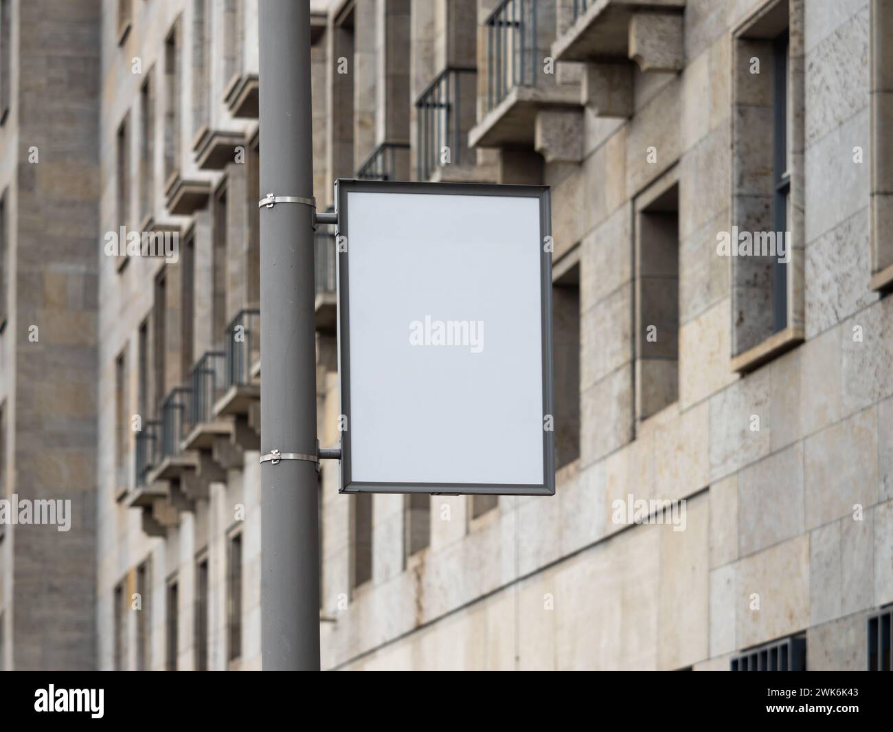 Werbemockup auf einer Straßenlaterne. Leere Vorlage für ein Poster in einer Stadt. Grauer Rahmen, montiert an einem Lampenträger neben dem Bürgersteig. Stockfoto