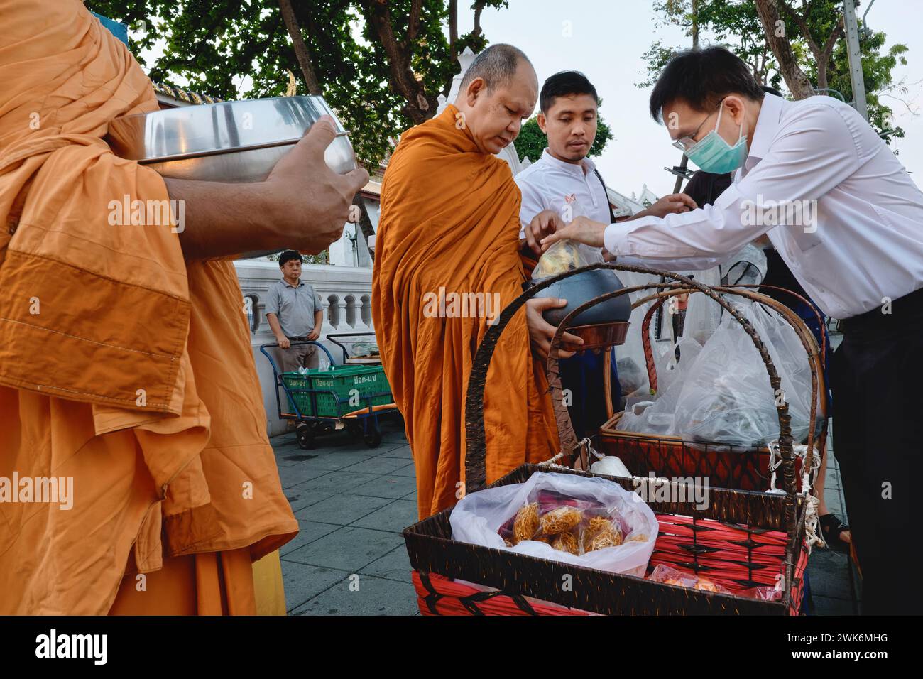 Während ihrer traditionellen Morgenalmosen in Bangkok, Thailand, erhalten thailändische buddhistische Mönche von einem gut zu erledigenden Laien Taschen mit Essen Stockfoto