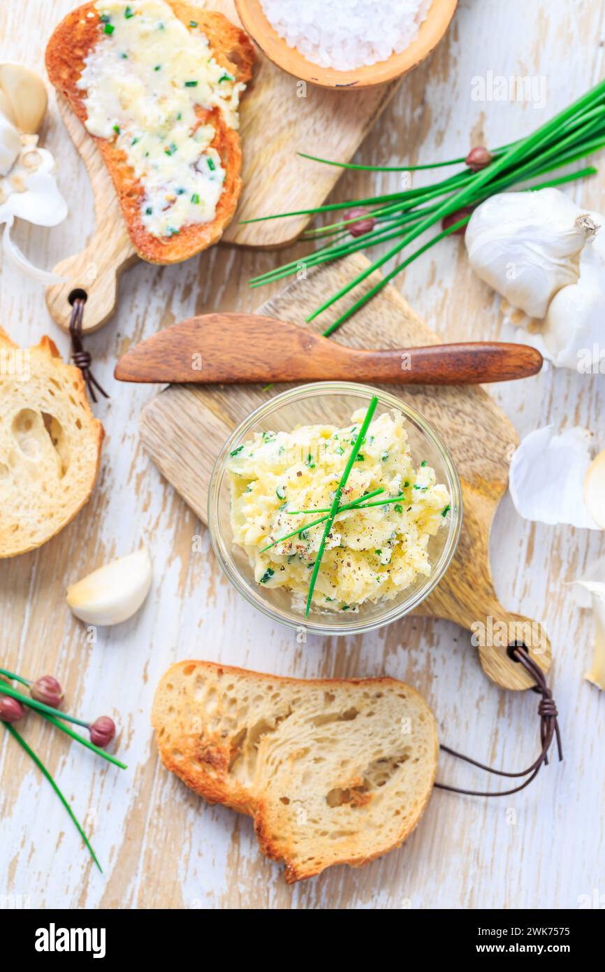 Hausgemachte Knoblauchbutter mit Schnittlauch und frisch geröstetem Baguette mit Salz Stockfoto