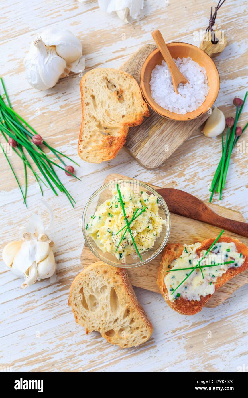 Hausgemachte Knoblauchbutter mit Schnittlauch und frisch geröstetem Baguette mit Salz Stockfoto