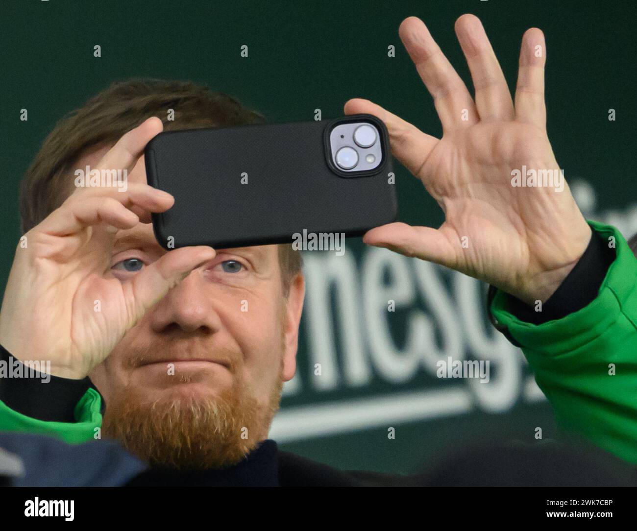 Aue, Deutschland. Februar 2024. Fußball: 3. Liga, FC Erzgebirge Aue - SG Dynamo Dresden, Spieltag 26, Erzgebirgsstadion. Michael Kretschmer (CDU), Ministerpräsident von Sachsen, filmt mit seinem Smartphone. Robert Michael/dpa/Alamy Live News Stockfoto