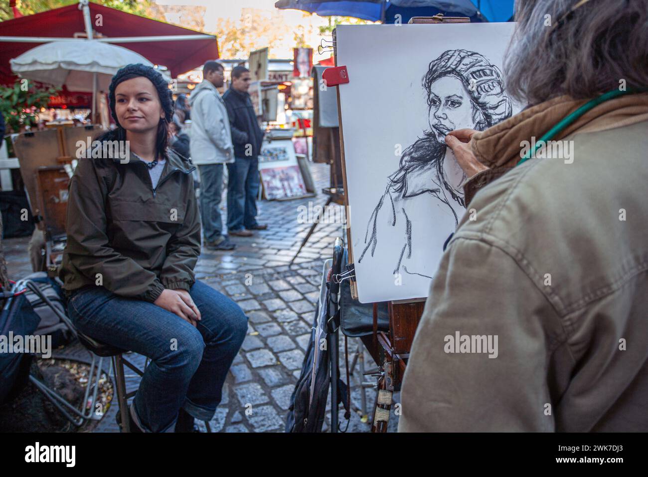 Ein Maler zeichnet eine junge Frau am Place du Tertre, dem berühmten Künstlerplatz und Touristenattraktion in Montmartre, Paris. Stockfoto