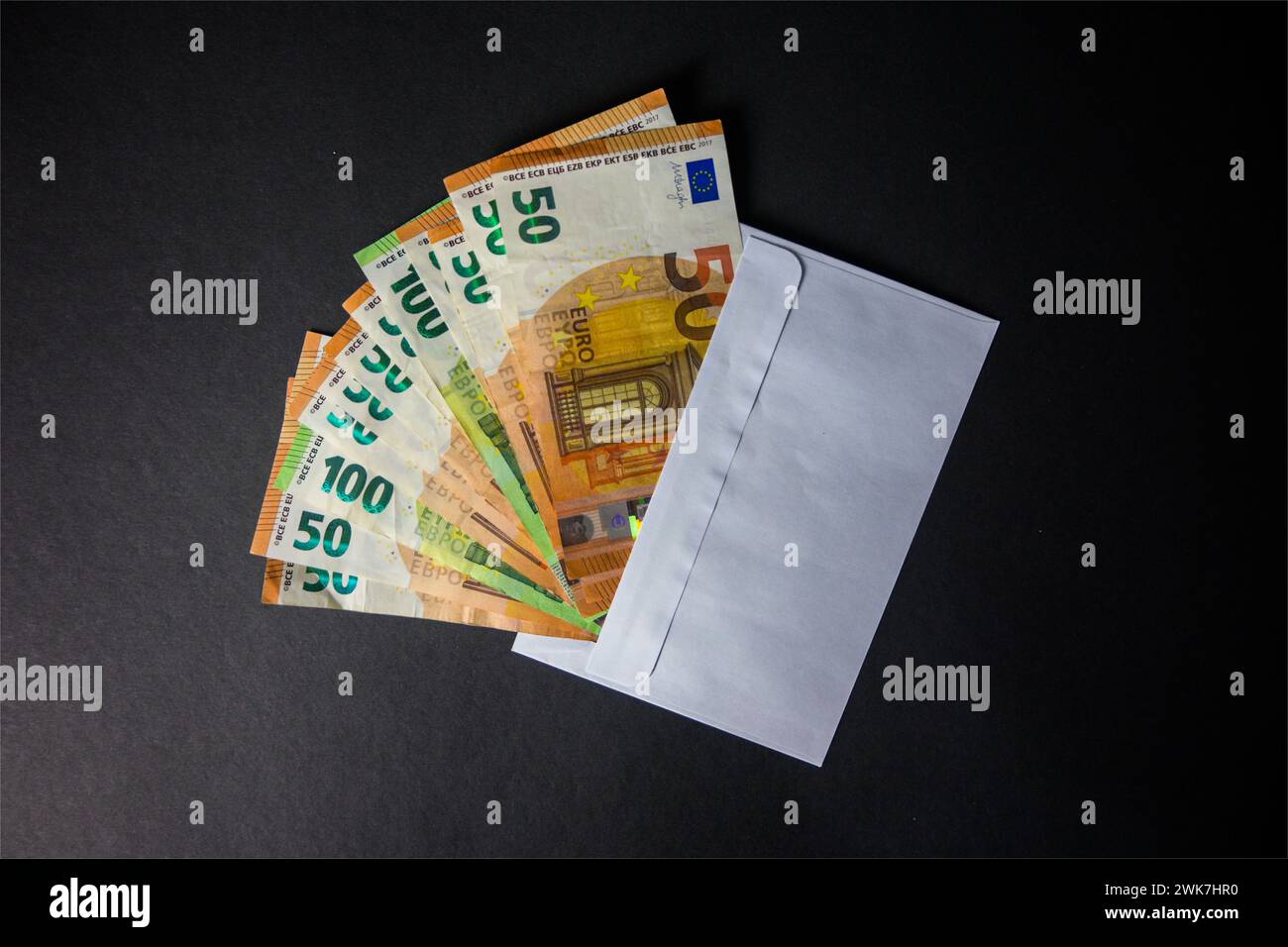 Eurogeld ragt aus dem Umschlag auf schwarzem Hintergrund - Draufsicht. Stockfoto