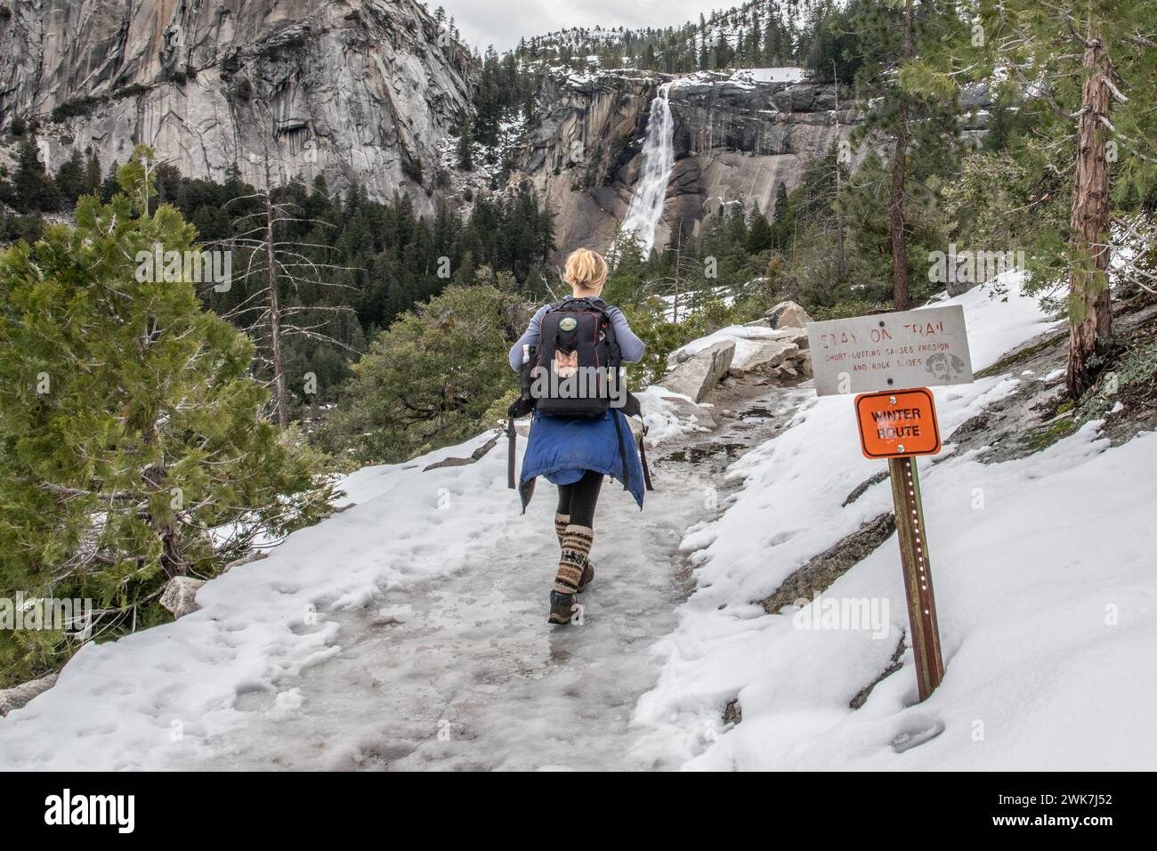 Wandern Sie im Yosemite National Park in den Bergen der Sierra Nevada, Kalifornien, auf einer verschneiten und vereisten Winterroute zu einem Wasserfall in der fernen Landschaft. Stockfoto