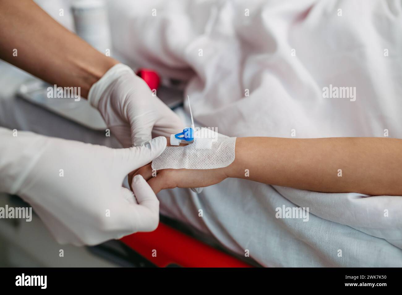 Nahaufnahme einer Schwester, die IV-Kanüle in die Vene einführt, Hand eines kleinen Mädchens. IV, intravenöse Therapie für den kindlichen Patienten. Stockfoto