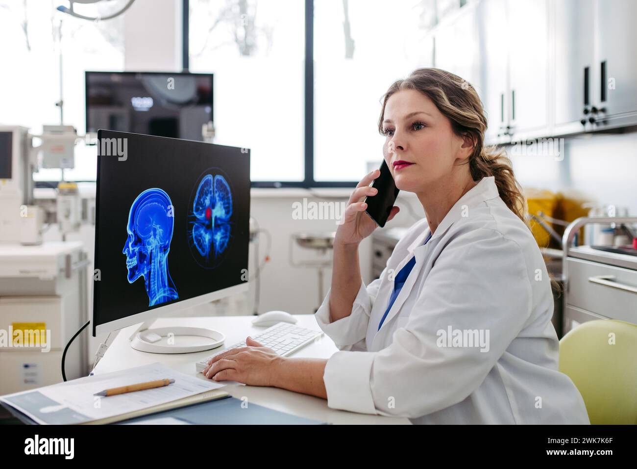 Ärztin, die am Computer in der Arztpraxis arbeitet, sich einen MRT-Scan ansieht, die Testergebnisse an den Patienten ruft. Arztkonsultationsscan mit dem Othe Stockfoto