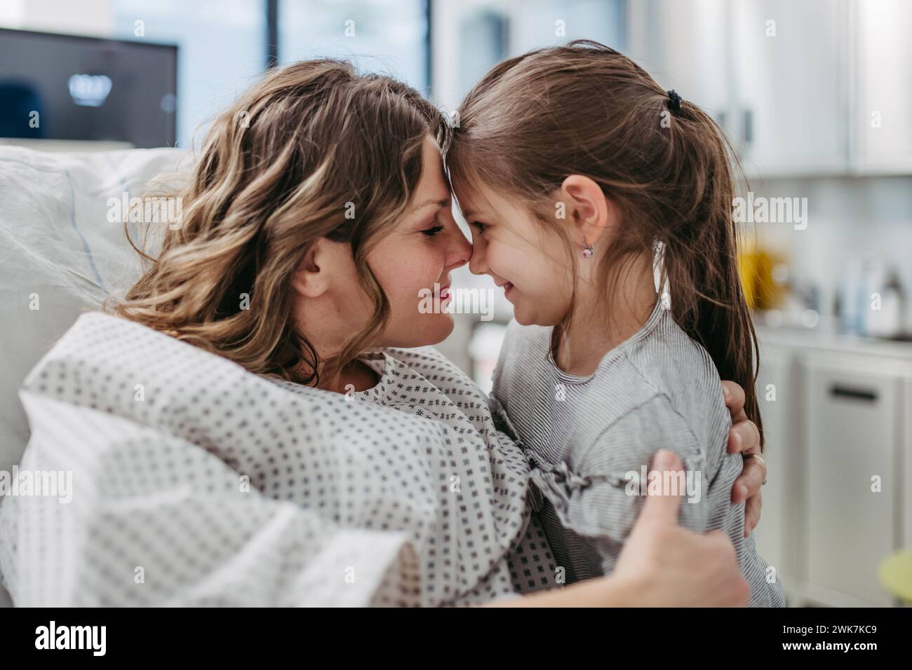 Tochter besucht Mutter im Krankenhaus nach erfolgreicher Operation und umarmt sie. Emotionale Unterstützung durch die Familie für Patienten im Krankenhaus. Stockfoto