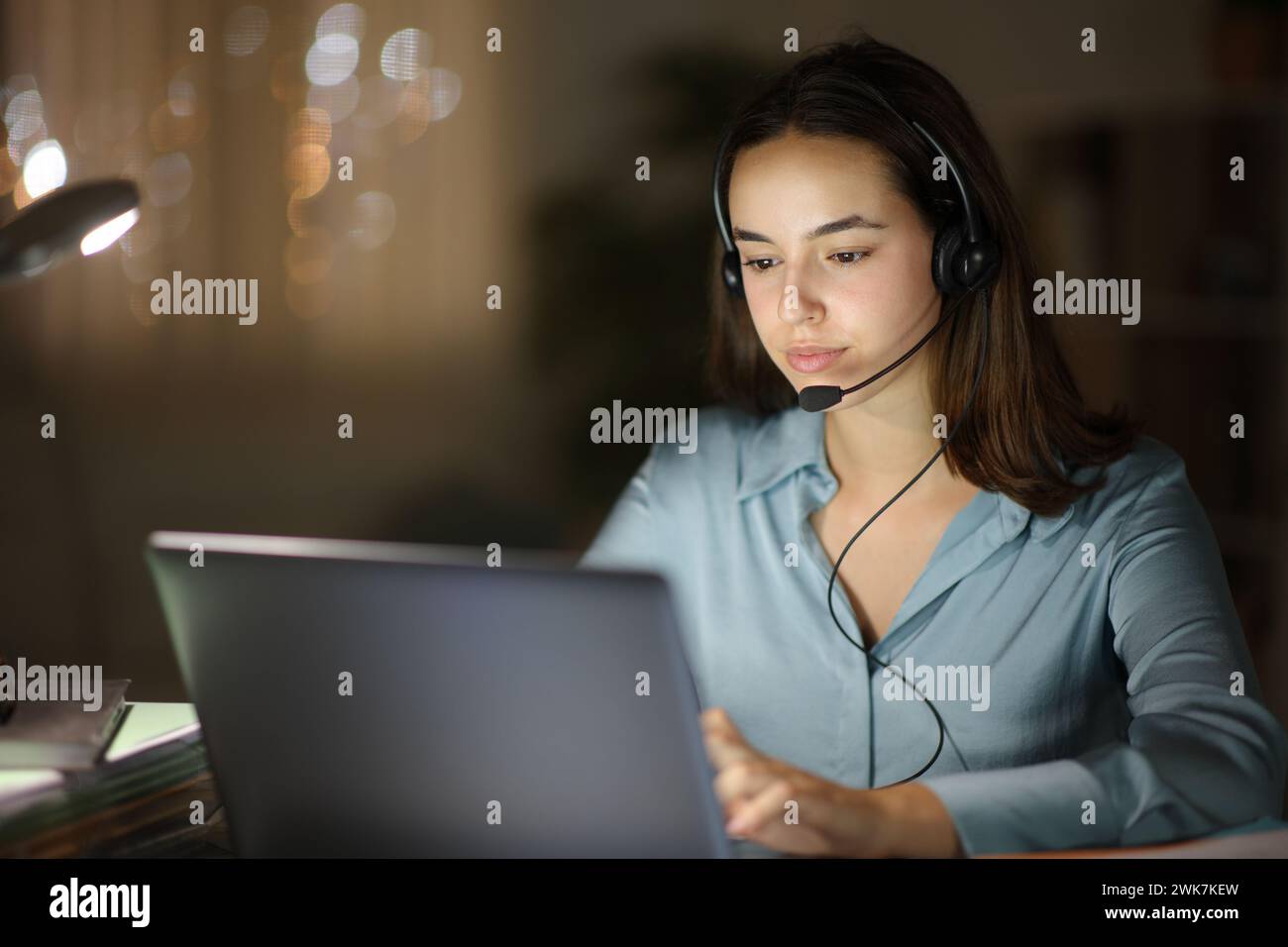 Tele-Bediener, der nachts zu Hause online arbeitet Stockfoto