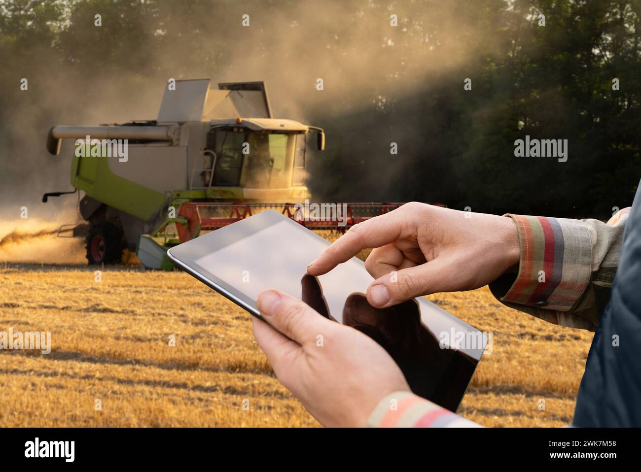 Landwirt mit digitalem Tablet auf dem Hintergrund des Ernteers. Smart-Farming-Konzept Stockfoto