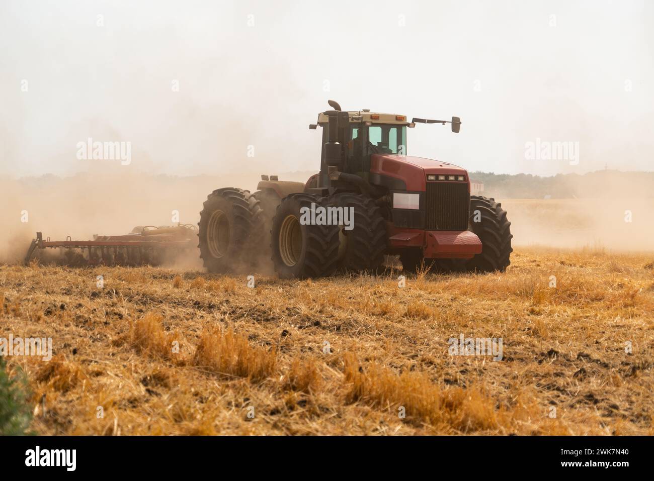 Ein Traktor mit Pflug pflügt das Feld nach der Ernte Stockfoto