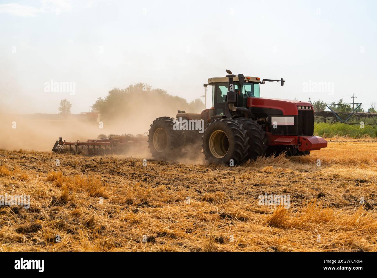 Ein Traktor mit Pflug pflügt das Feld nach der Ernte Stockfoto
