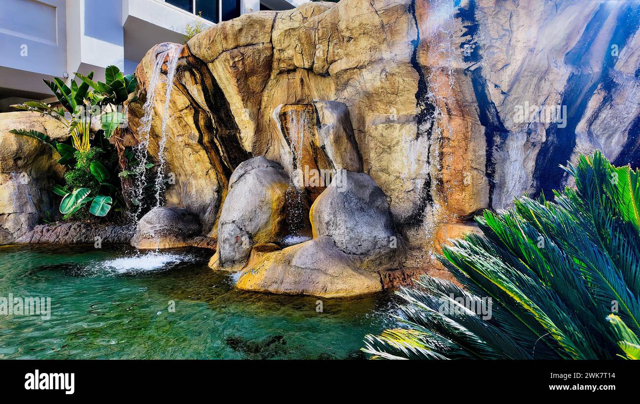 Eine künstliche Felsformation mit Wasser, das in einen ruhigen Pool im Tropicana Las Vegas Hotel stürzt Stockfoto