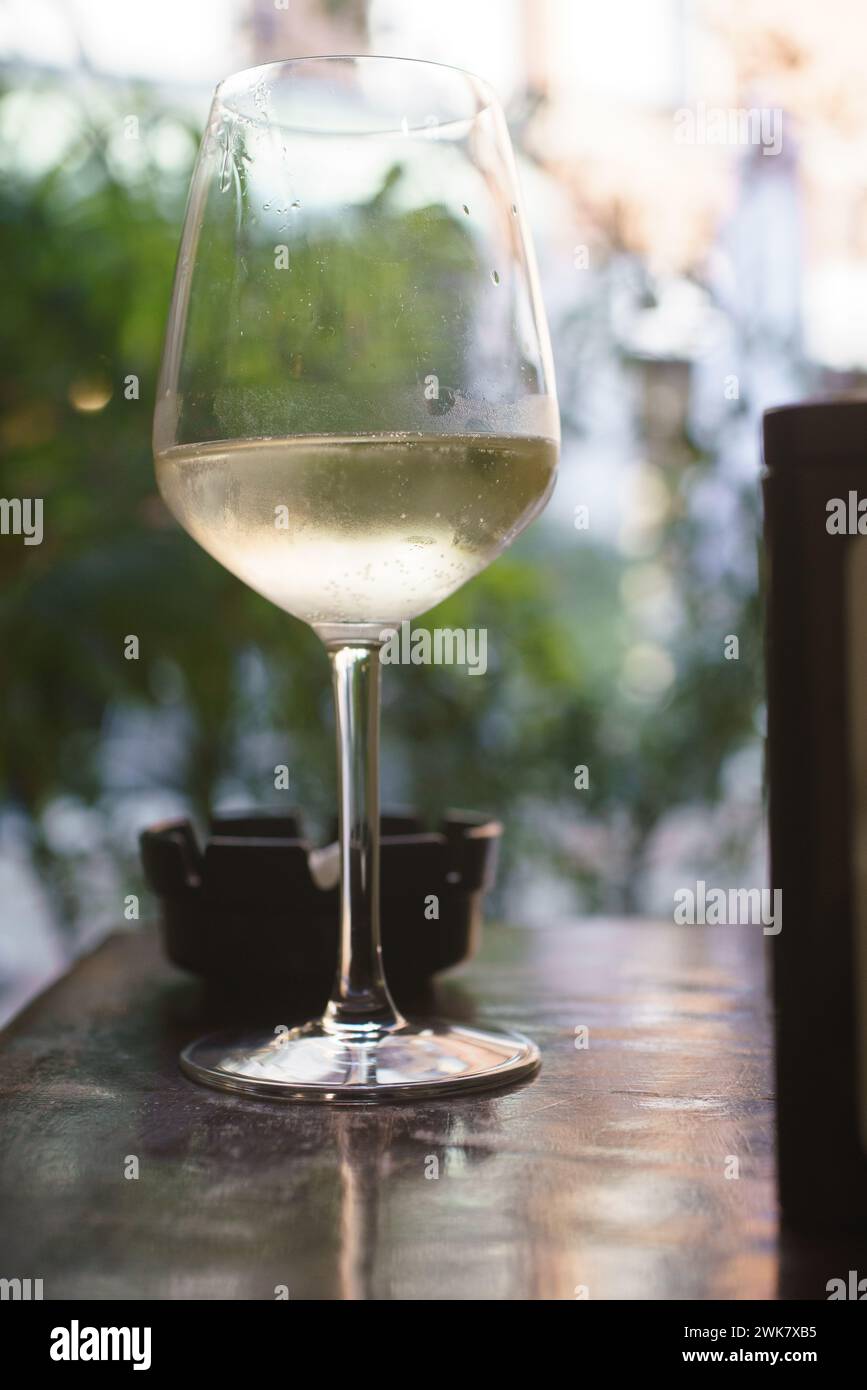 Eine Person sitzt an einem Tisch mit einem Glas Prosecco-Weißwein. Sie scheinen einen Moment der Entspannung, des Genusses zu genießen Stockfoto