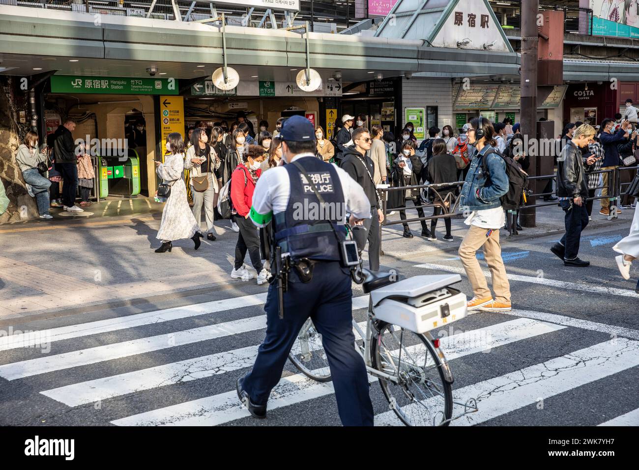 Ein männlicher Polizeibeamter aus Tokio schiebt sein Fahrrad über den Pelikanübergang am Bahnhof Harajuku, Tokio Bezirk, Japan, Asien, 2023 Stockfoto