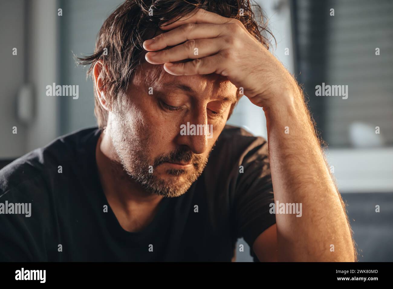 Einsamer und depressiver erwachsener Mann mit geschlossenen Augen zu Hause. Unrasierter Mann traurig und unglücklich. Psychische Gesundheit und Bedauerungskonzept. Selektiver Fokus. Stockfoto