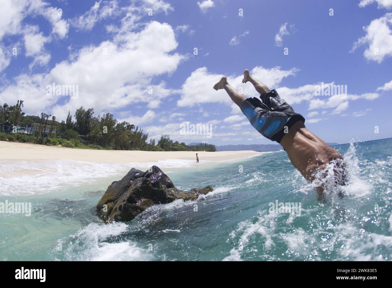 Ein Mann taucht vom Felsen in Meereswellen. Stockfoto