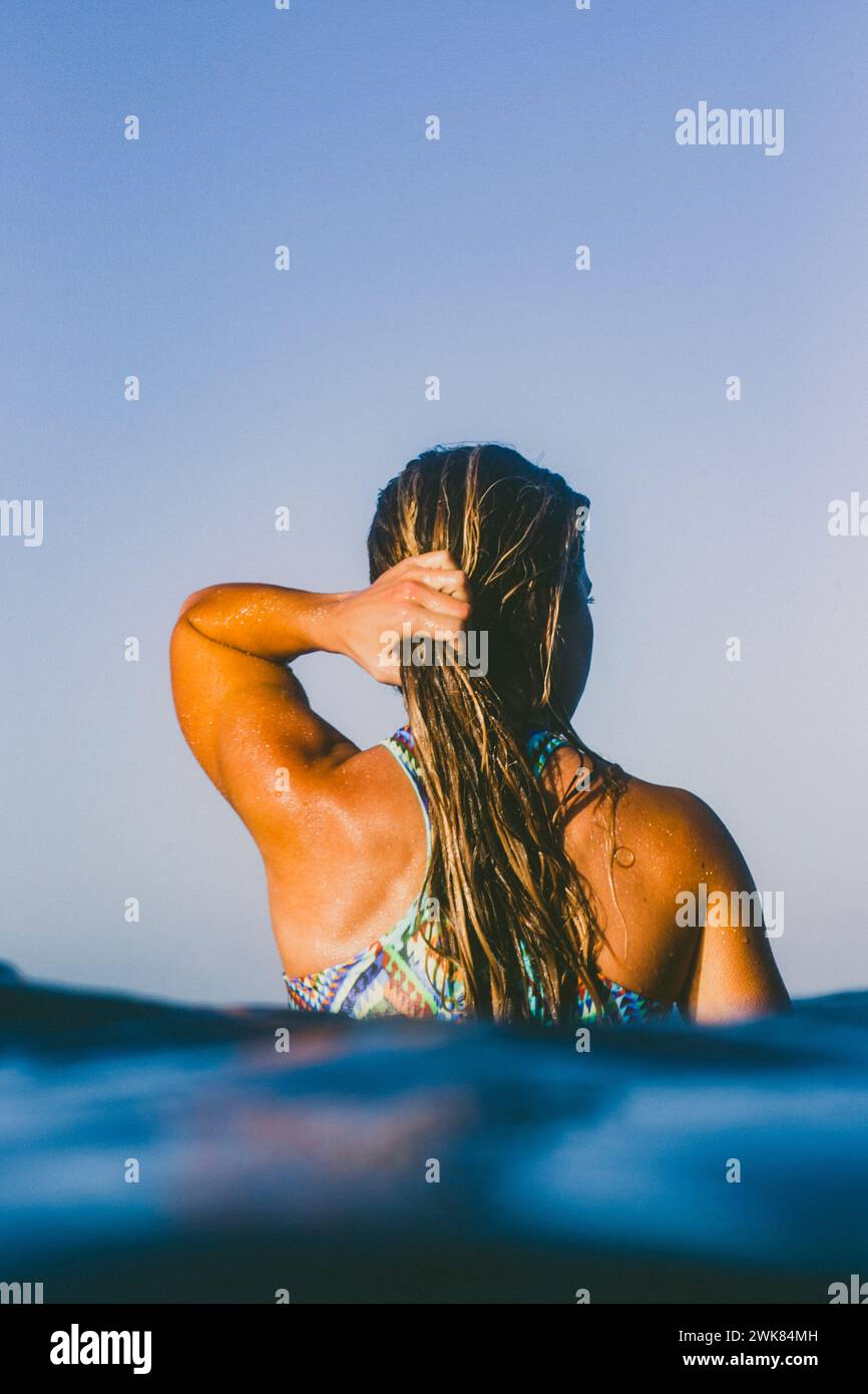Ein Mädchen wartet auf Eine Welle, die auf ihrem Surfbrett sitzt Stockfoto