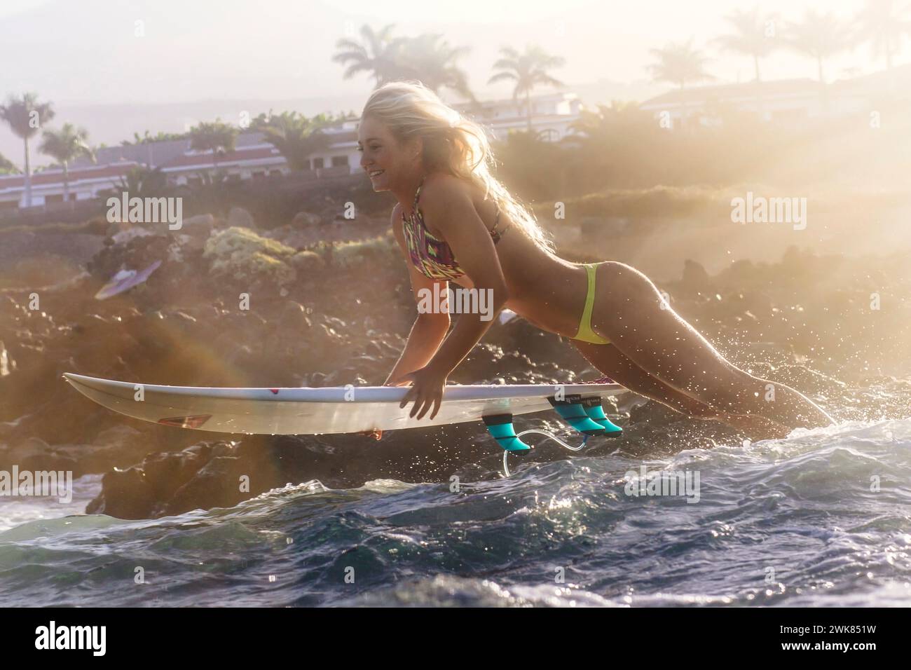 Eine Surferin im Bikini springt mit ihrem Surfbrett ins Wasser Stockfoto