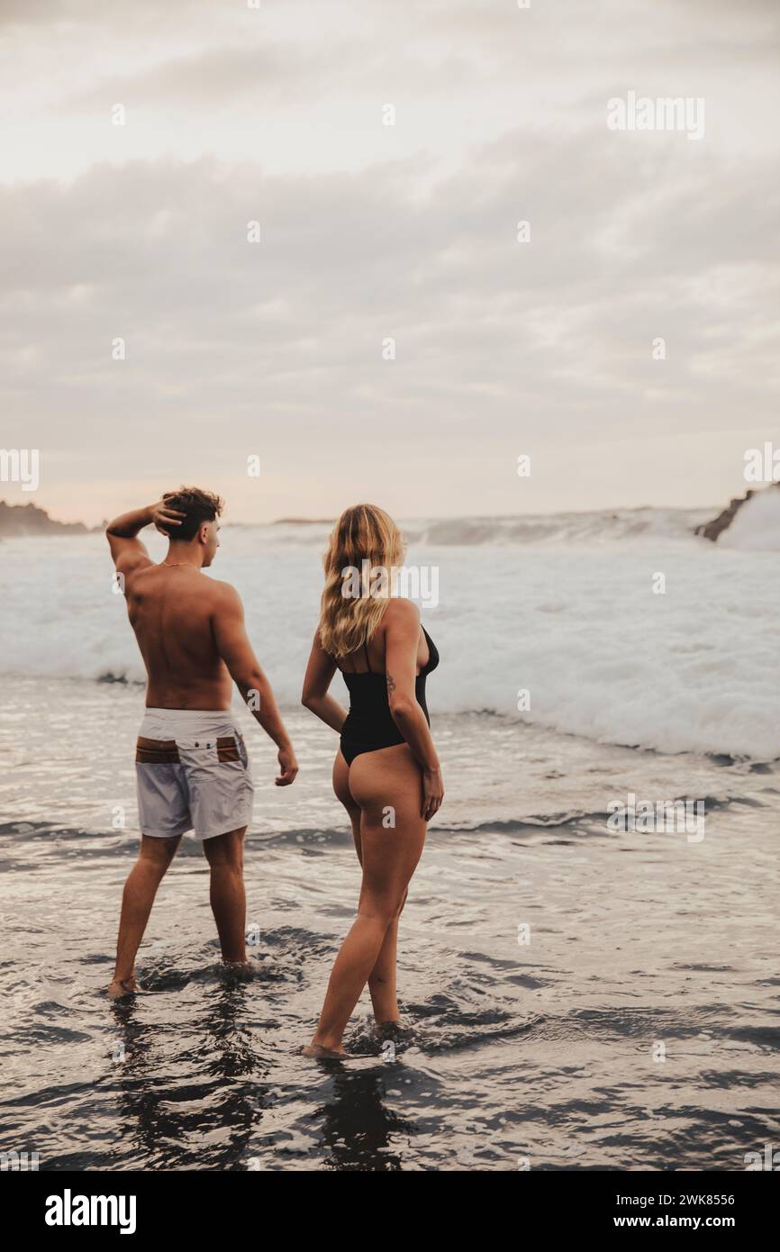 Paare, die während des Sonnenuntergangs an einem schönen Strand auf Teneriffa baden Stockfoto