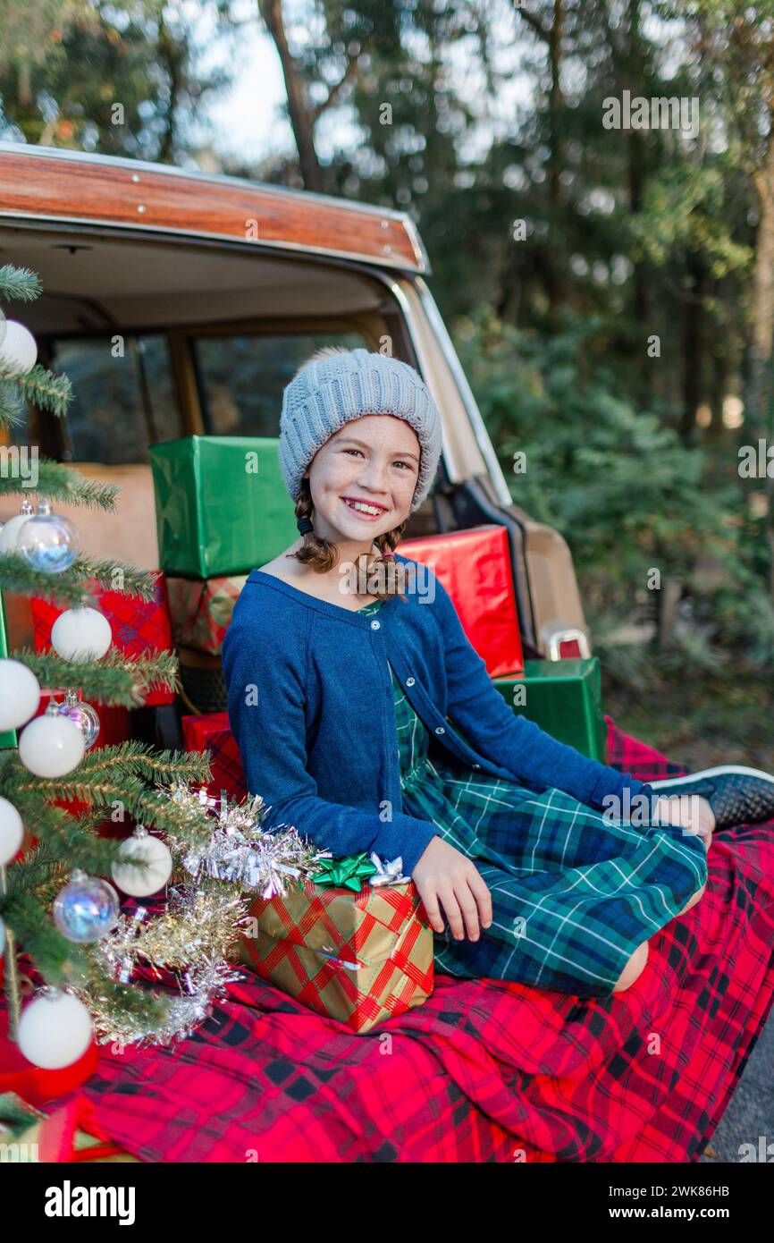 Das junge Mädchen sitzt mit Weihnachtsgeschenken auf der Rückseite eines Oldtimers Stockfoto