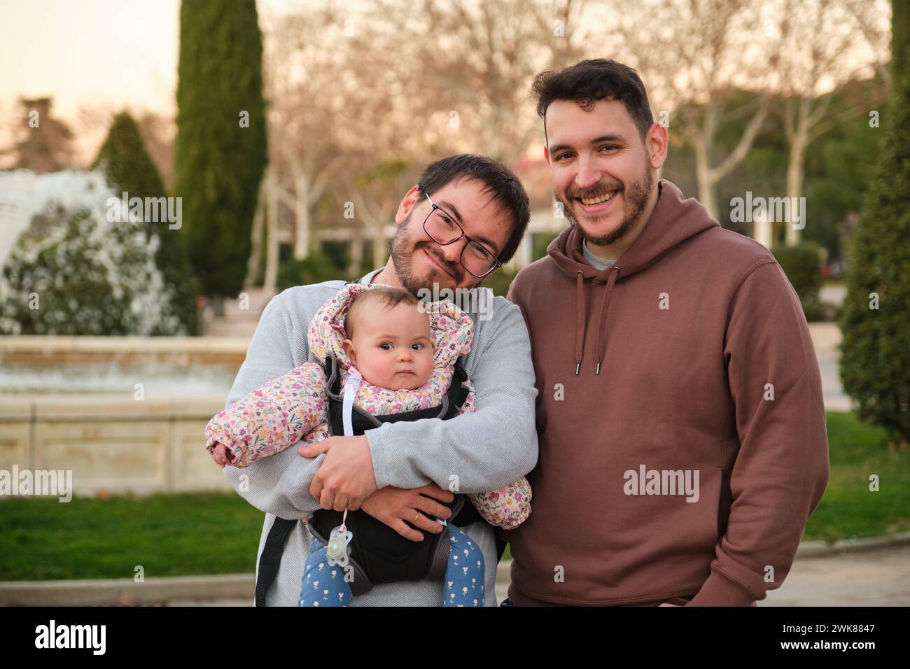 Homosexuelles glückliches Paar mit ihrem 6 Monate alten Baby in einer Babytrage. Stockfoto