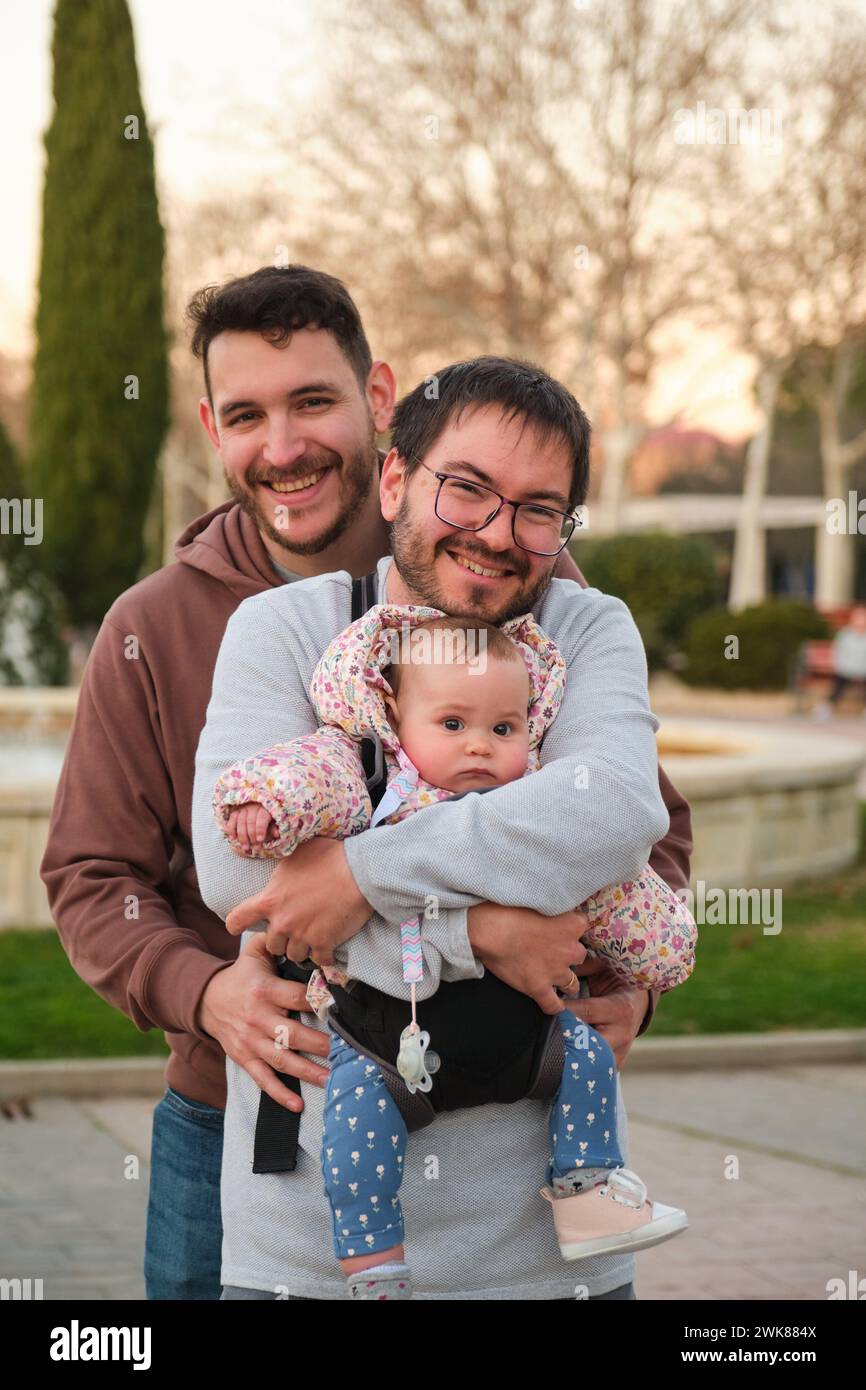 Porträt eines schwulen glücklichen Paares mit 6 Monate altem Baby in einer Babytrage. Stockfoto