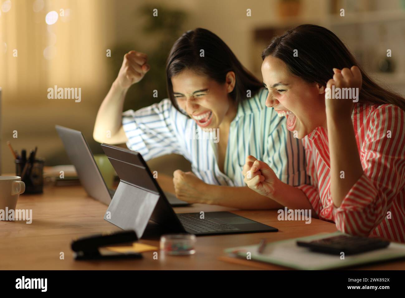 Begeisterte Tele-Mitarbeiter feiern Online-Nachrichten in der Nacht zu Hause Stockfoto