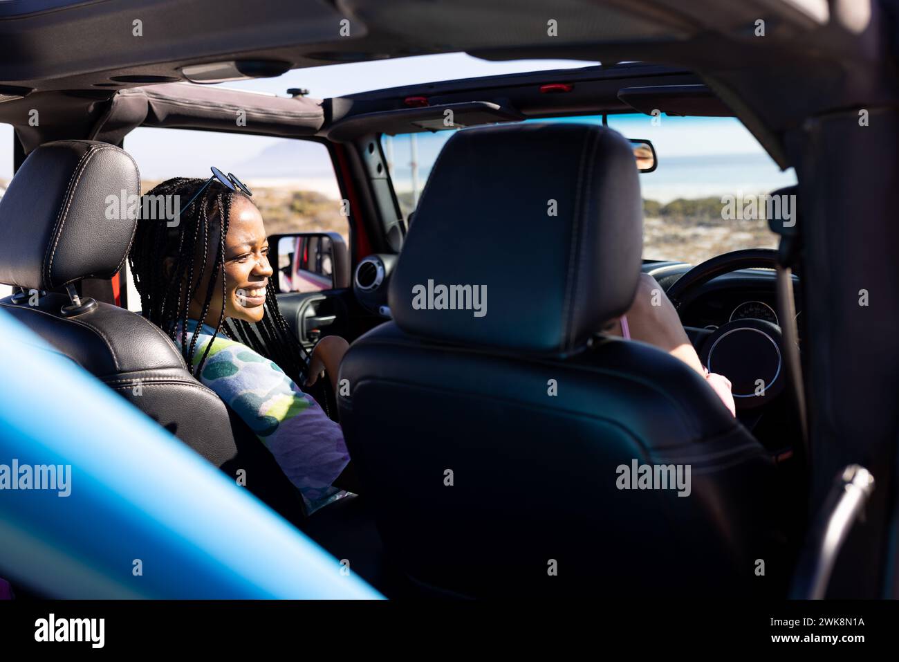 Die junge afroamerikanische Frau fährt gern mit dem Auto auf einem Roadtrip Stockfoto