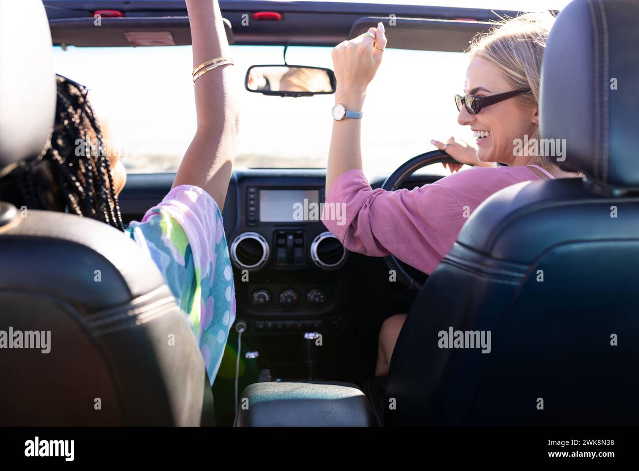 Junge afroamerikanische Frau und junge kaukasische Frau genießen eine gemeinsame Autofahrt auf einem Roadtrip Stockfoto