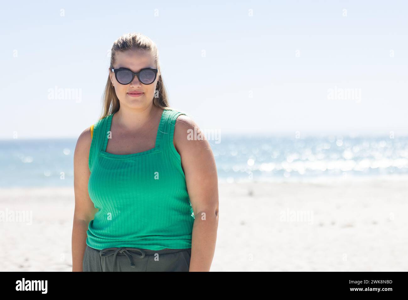 Junge Weiße in Übergröße steht selbstbewusst an einem sonnigen Strand, mit Kopierraum Stockfoto