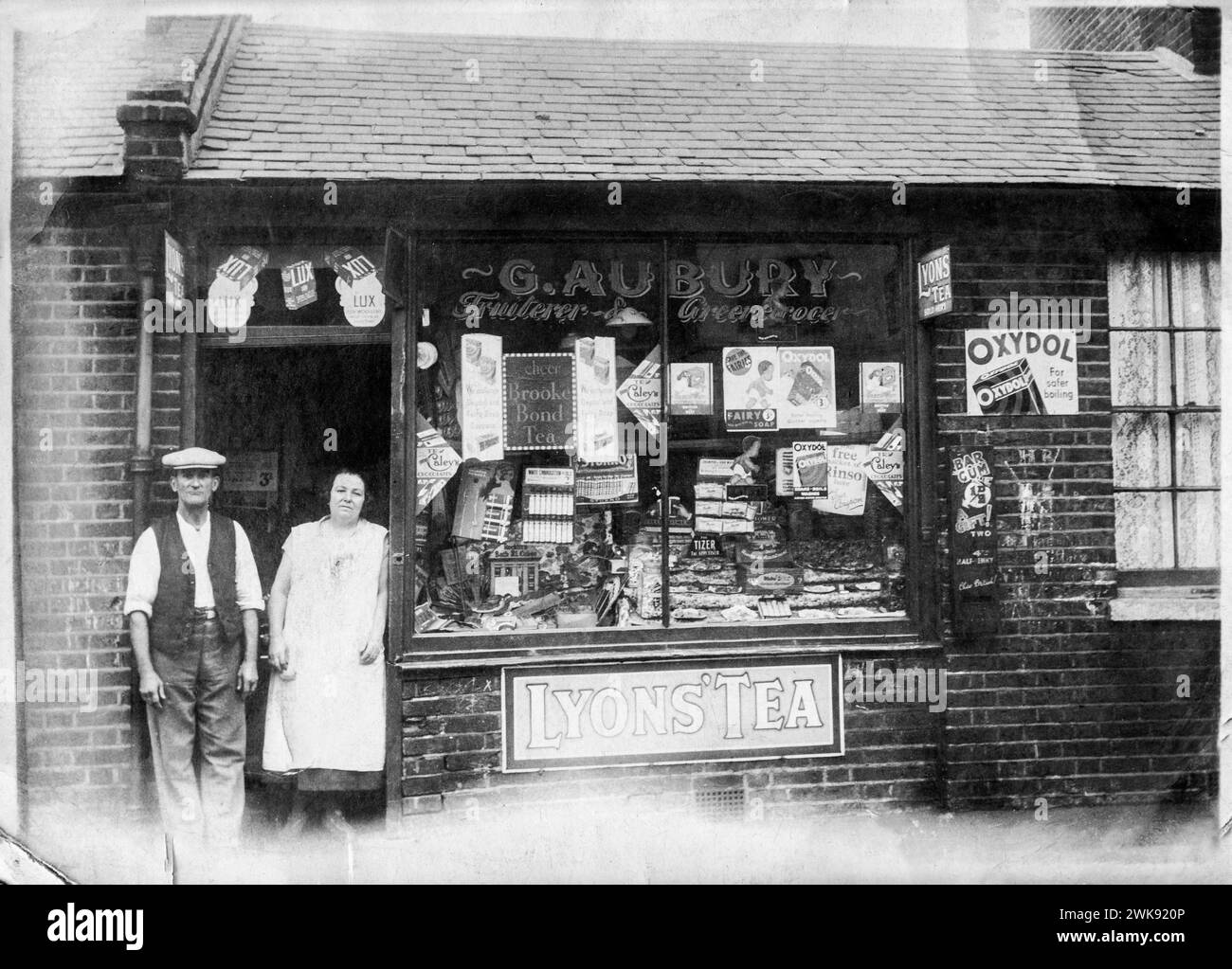 Schwarz-weiß-Familienschnappschuss von George Aubury und seiner Schwägerin Caroline Aubury, vor ihrem Familienobst- und Lebensmittelladen in der Battersea Park Road, South London, Anfang der 1930er Jahre Stockfoto