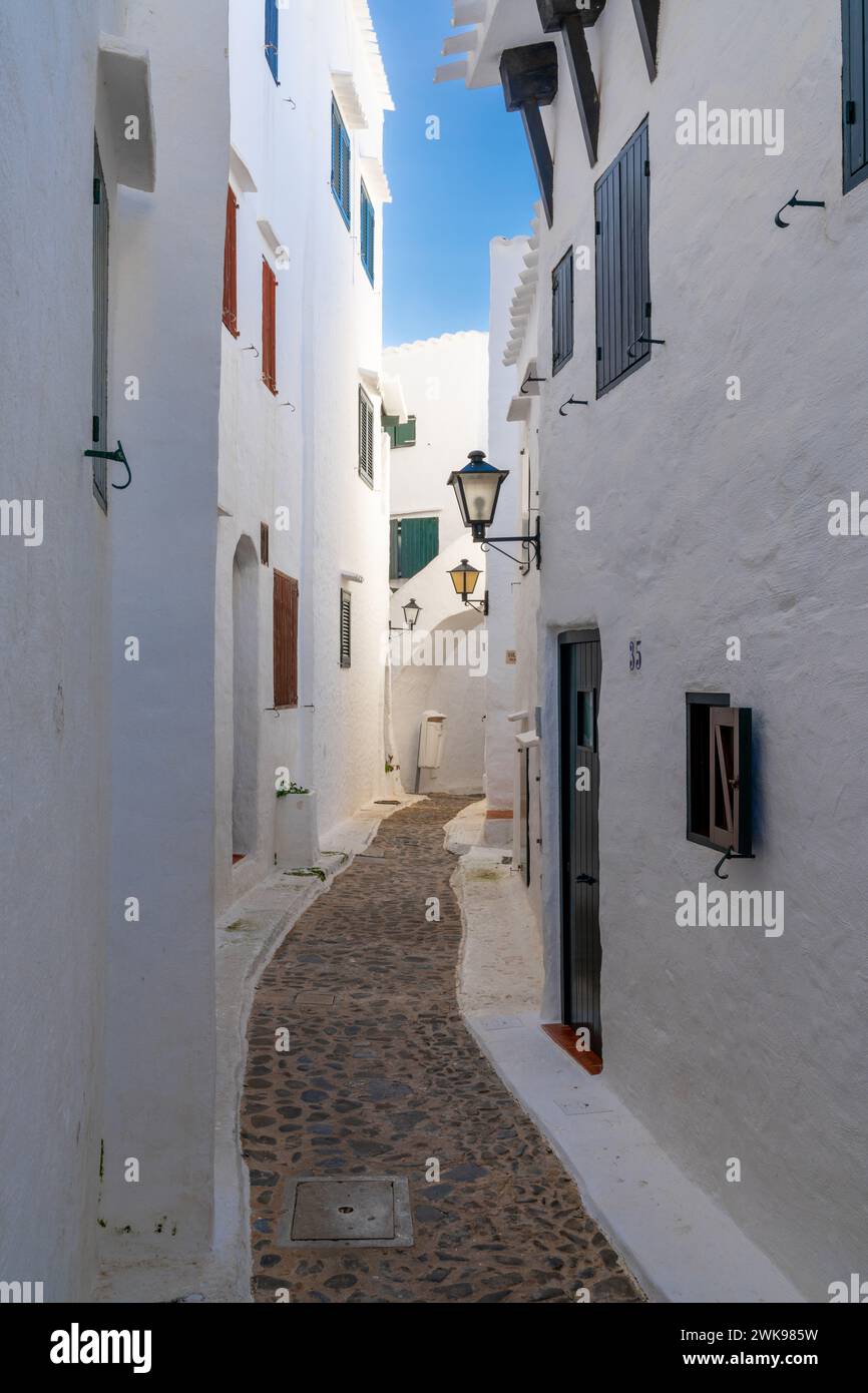 Binibeca Vell, Spanien - 24. Januar 2024: Enge Gasse führt durch ein Labyrinth von weiß getünchten Gebäuden im Dorfzentrum von Binibeca Vell Stockfoto