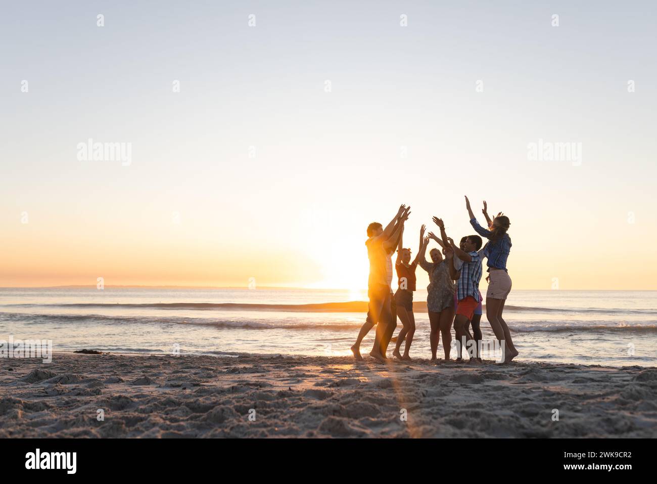 Verschiedene Freunde feiern am Strand bei Sonnenuntergang, mit Kopierraum Stockfoto