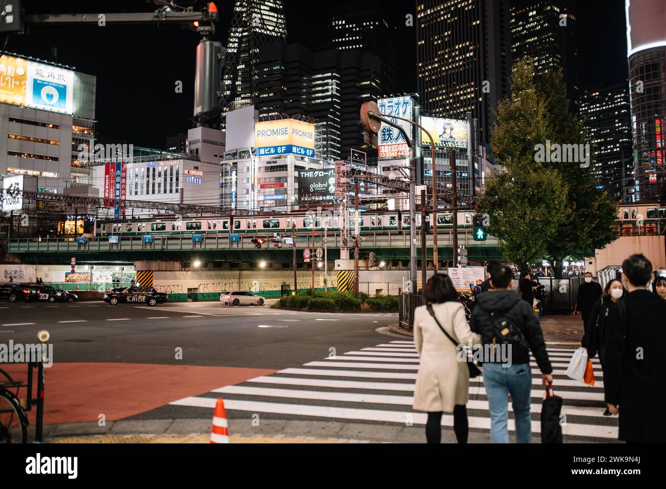 Ein lebhafter Abendblick auf die beleuchteten Straßen von Shinjuku und die geschäftige Menschenmenge. Stockfoto