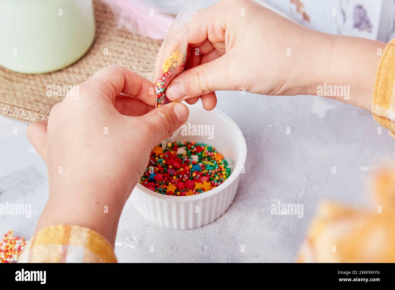 Süße der Ostertraditionen, wenn Kinder Kekse aus nächster Nähe mit Streuseln dekorieren. Stockfoto