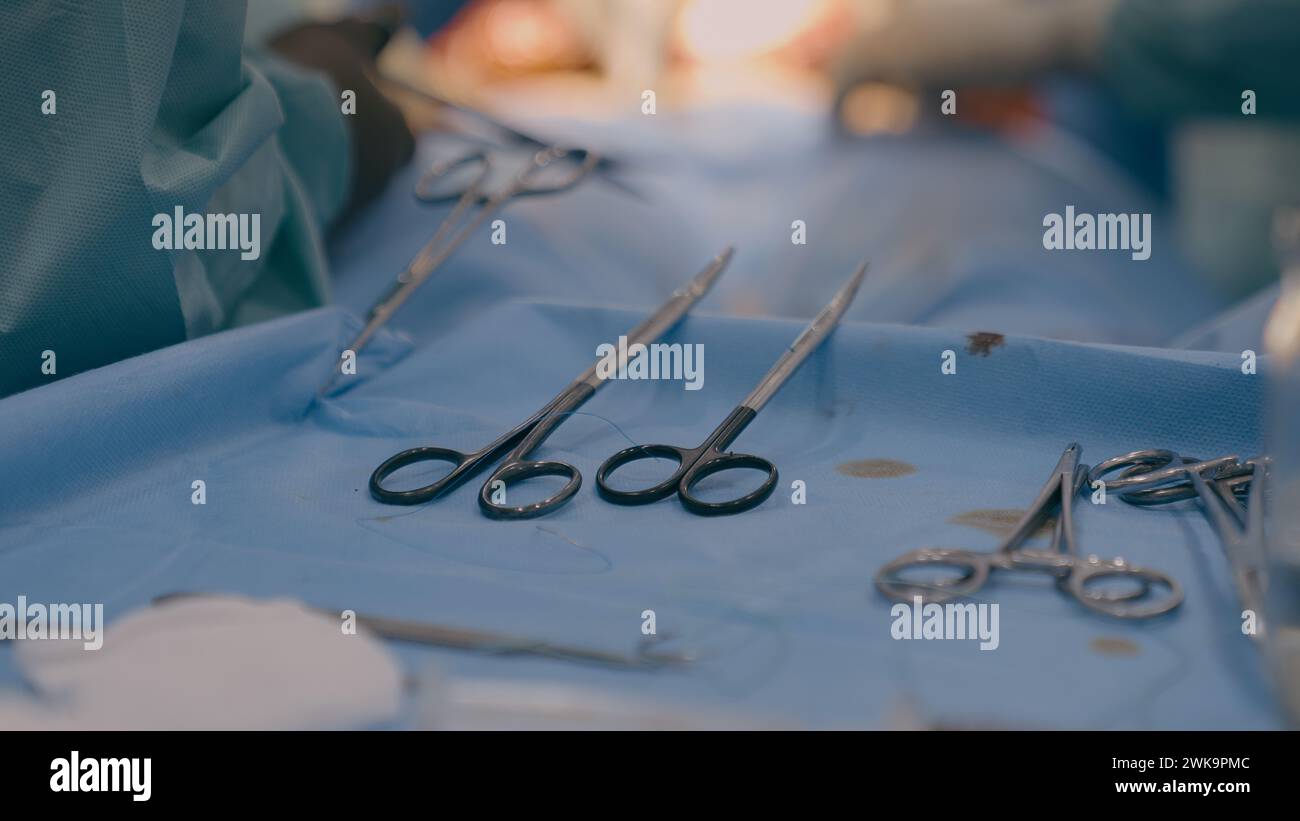 Schließen Sie mehrere chirurgische Werkzeuge auf dem Tisch im OP Team Chirurgen Ärzte führen medizinische Operation mit Skalpellen Pinzetten Schere chirurgische Stockfoto