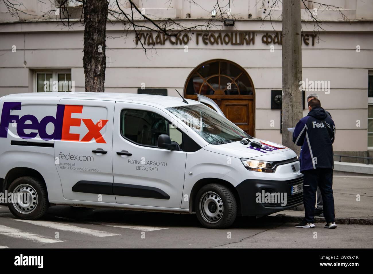 Ein FedEx-Lieferwagen steht neben einer Person auf einer Stadtstraße. Stockfoto