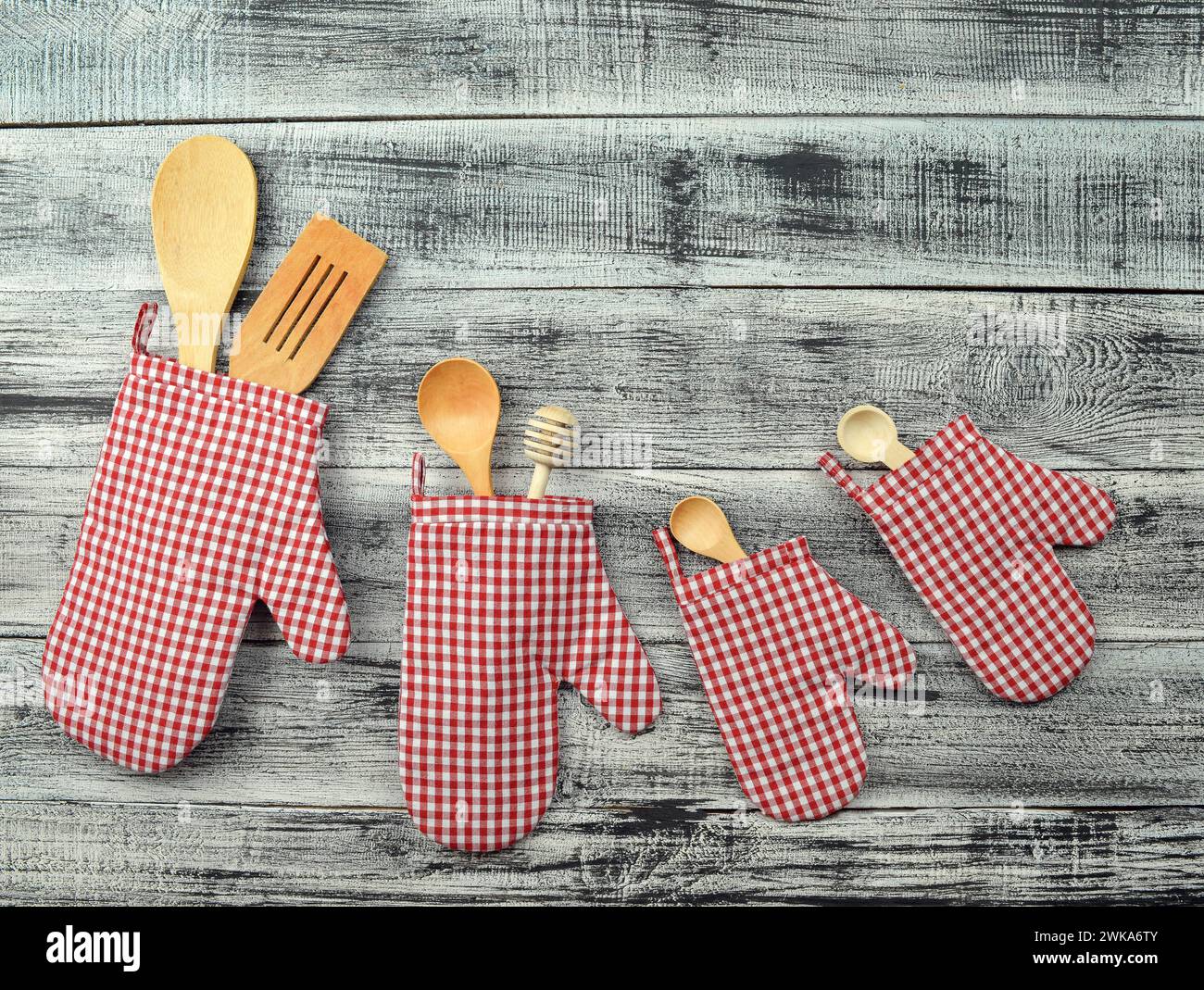 Küchenhandschuhe und Küchenutensilien auf hölzernem Hintergrund. Besteck auf Holzhintergrund. Foto für das Menü. Das Konzept des Wartens auf Essen. Heimkino Stockfoto
