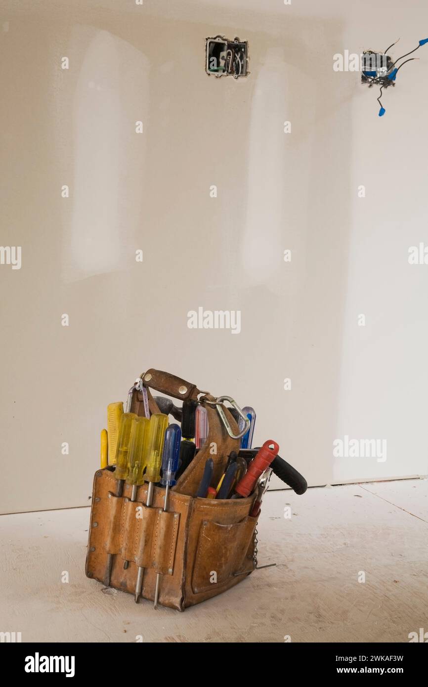 Werkzeugtasche aus Leder auf Sperrholzboden eines unfertigen Zimmers im Haus. Stockfoto