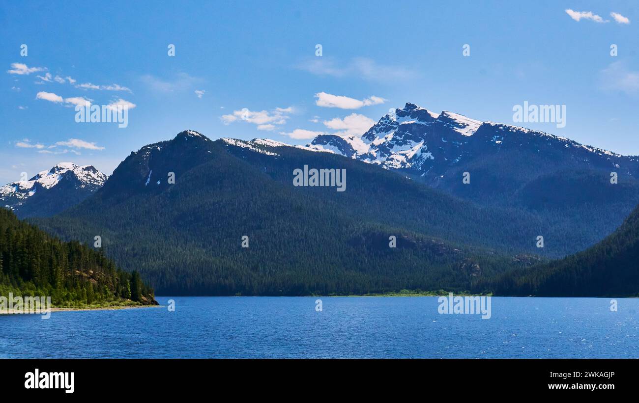 Blick von einem mit Treibholz bedeckten Meeresstrand in der Dämmerung mit bunten weichen Wolken in der Ferne. Stockfoto