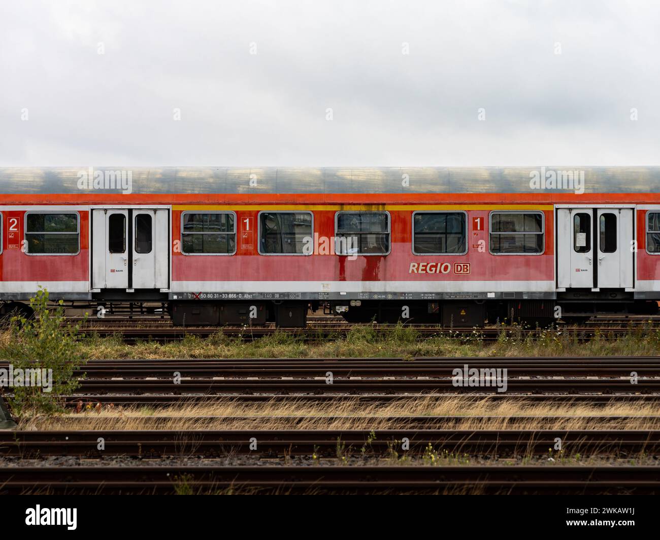 Der alte Pendlerzug der DB Regio wird außer Betrieb genommen. Verwittertes und verlassenes Fahrzeug für Passagiere, die auf einem leeren Bahngleis stehen Stockfoto
