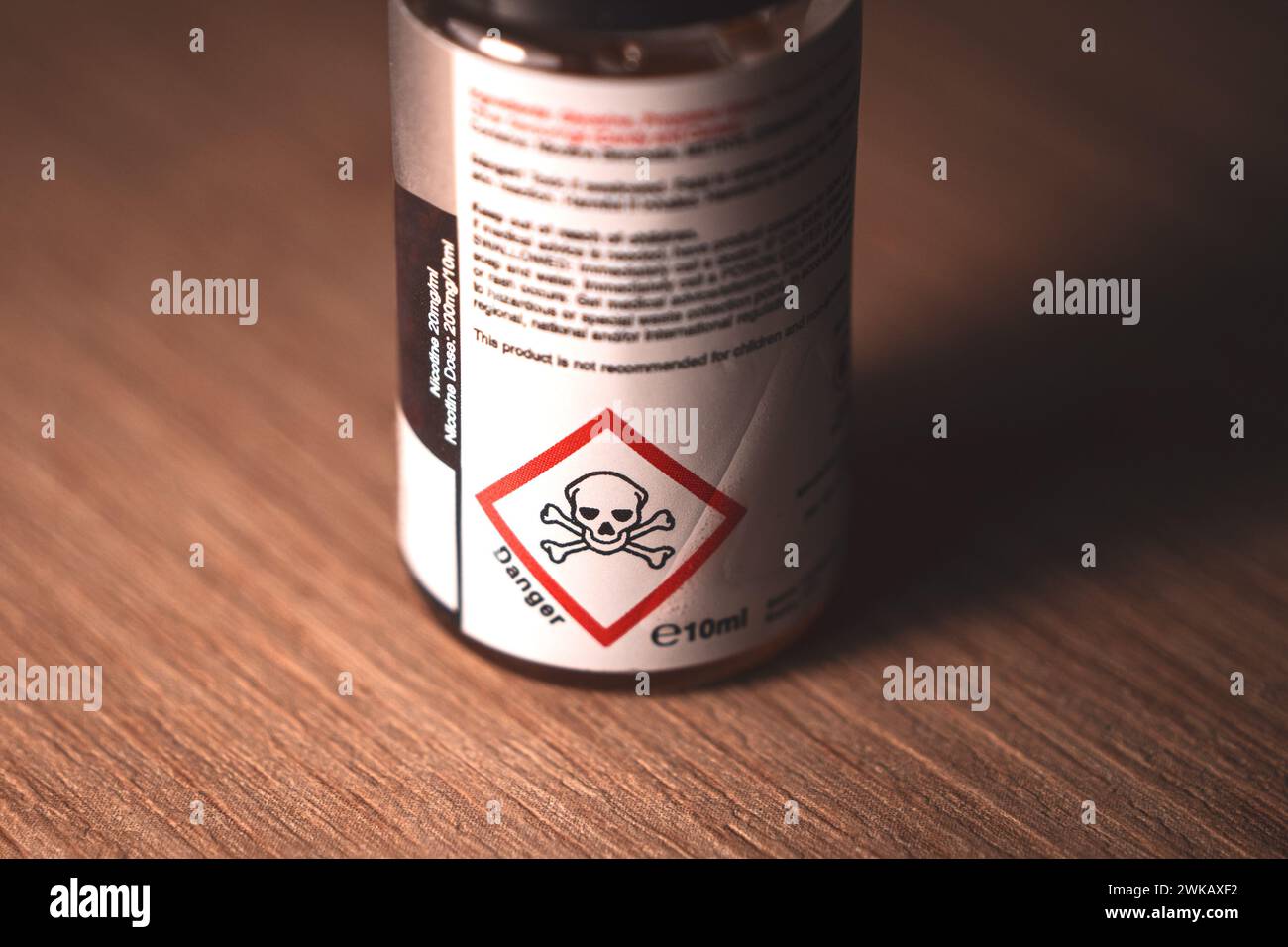 Vape Saftflasche mit Warnschild „Gefahr Schädel“ auf dem Etikett, Nahaufnahme mit Kopierraum. Stockfoto