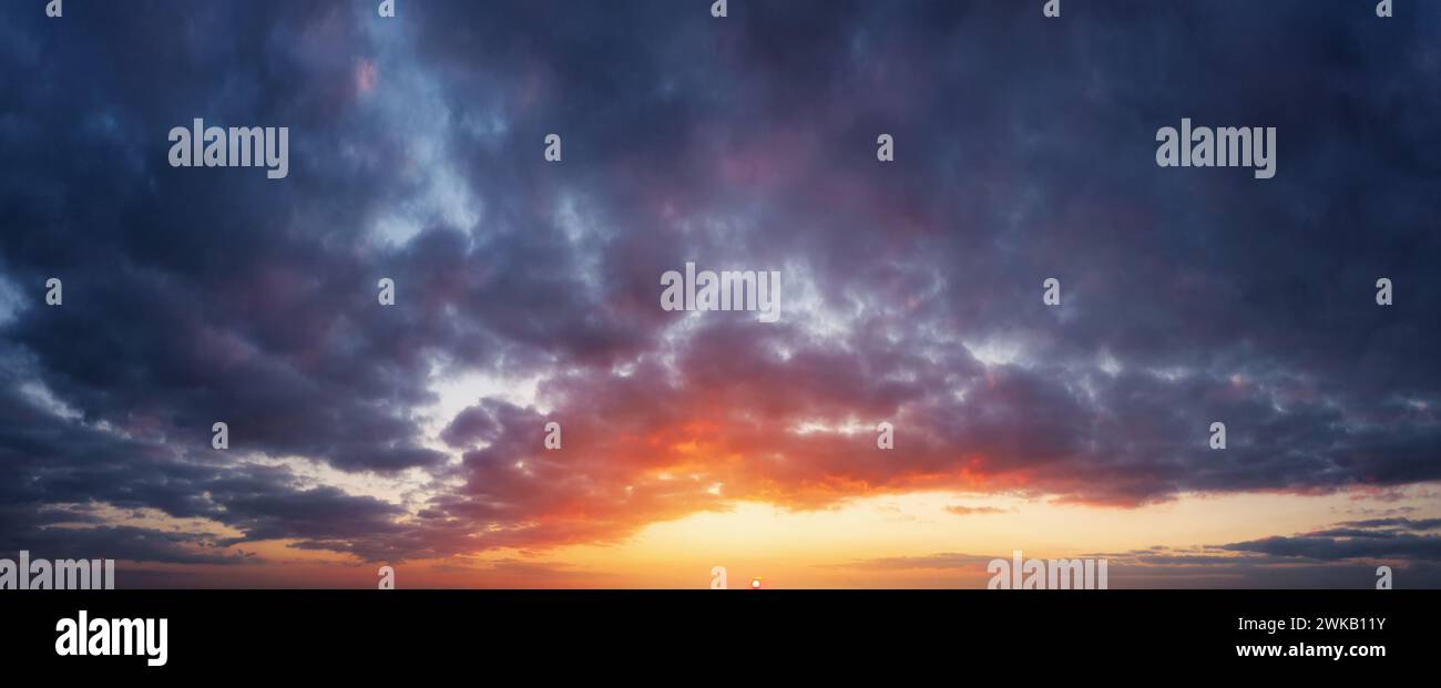 Bedeckter Himmel bei Sonnenuntergang. Die Sonne untergeht am Horizont, graue Vorregenwolken. Stockfoto