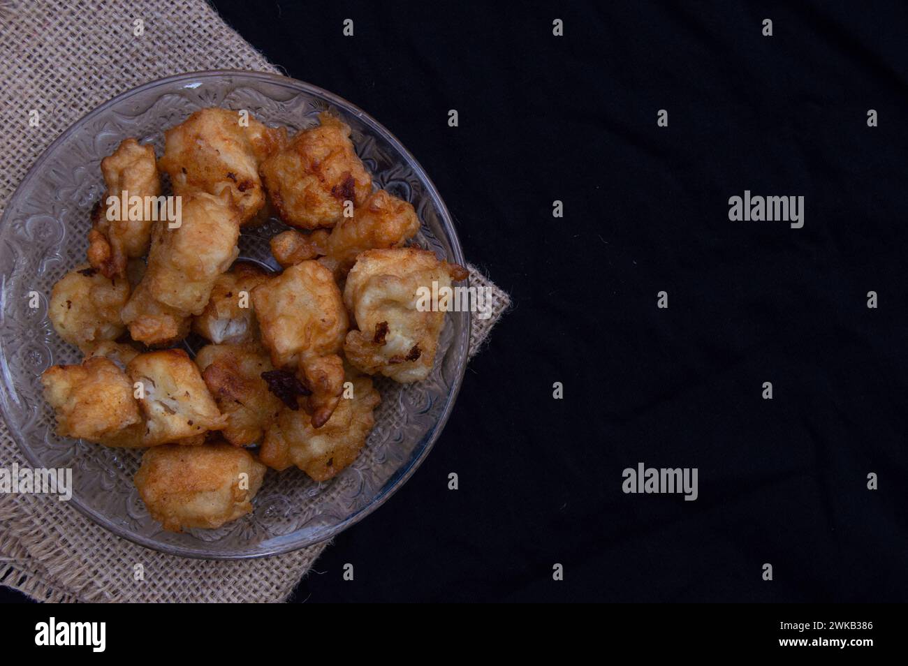 Tofu mit einer Schicht Mehl, das knusprig gebraten wird. Lebensmittelfotos mit schwarzem Hintergrund Stockfoto