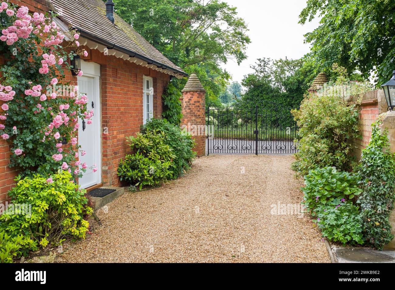 Englisches Landhaus und Garten mit Kieseinfahrt und schmiedeeisernen Toren. Stockfoto