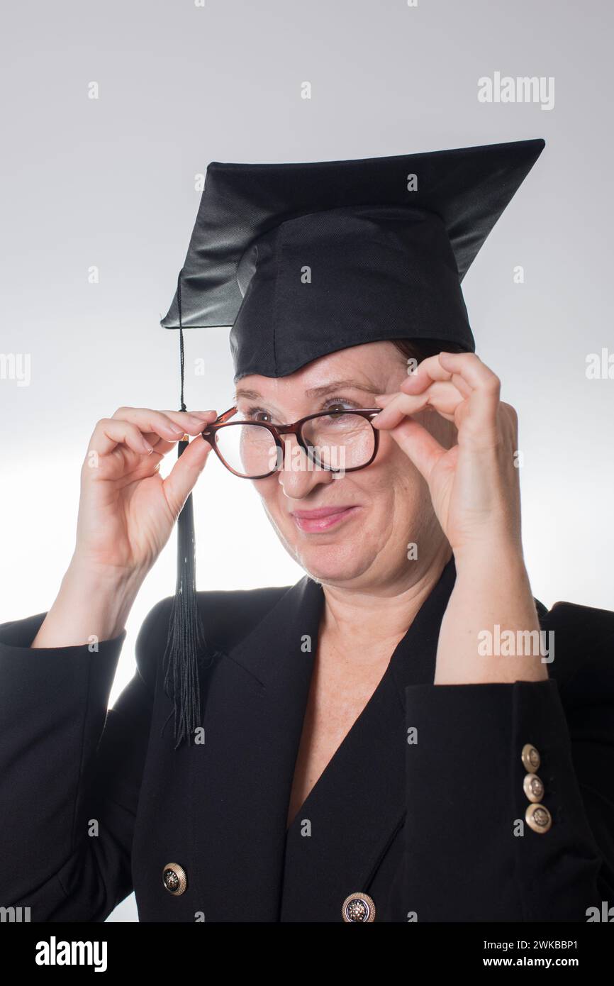 Reife Frau mit Brille und Graduiertenkappe. Weißer Hintergrund Stockfoto